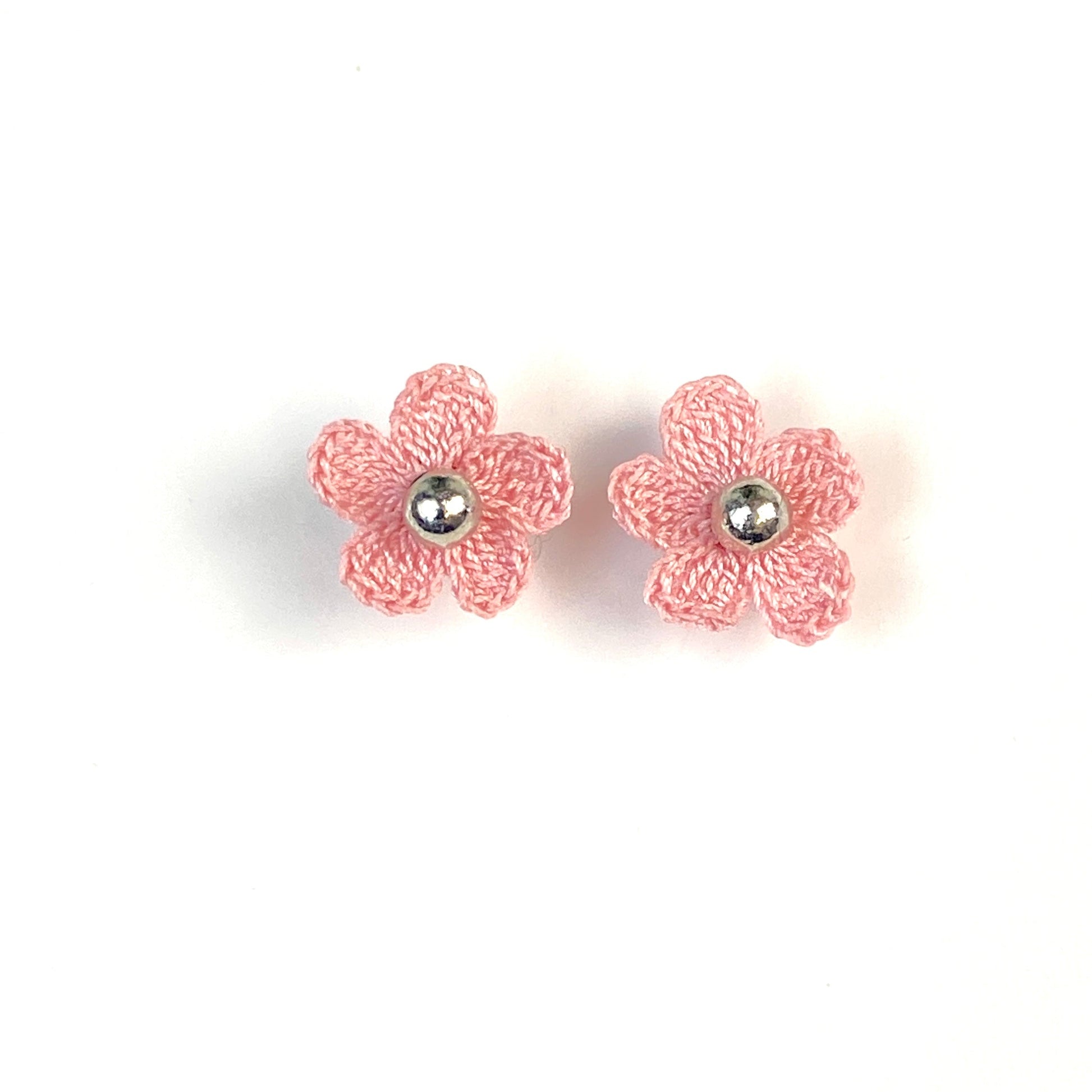Pair of light pink crochet flower earrings on a white background