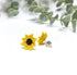 Yellow sunflower earrings on a white background with green leaves.