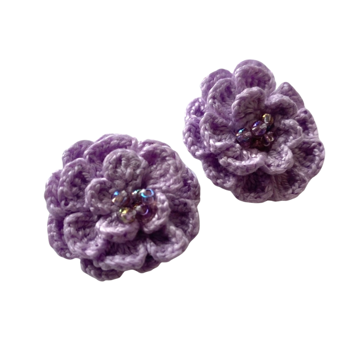 Two purple crocheted flower-shaped accessories with iridescent rhinestone centers, displayed on a plain white background.