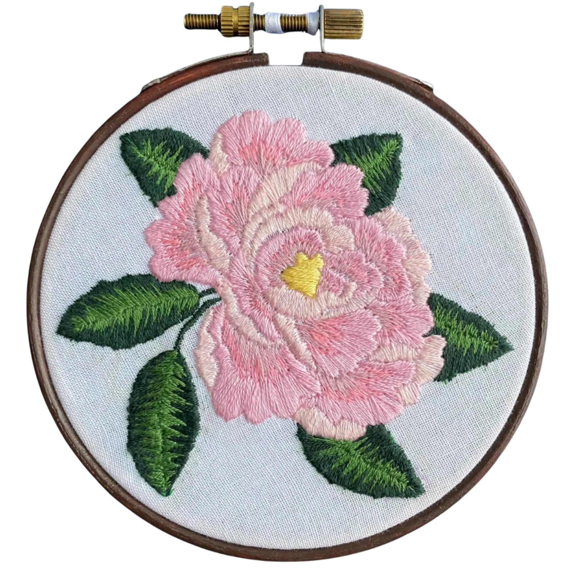 A circular embroidery hoop holding light blue fabric with a large pink flower and green leaves stitched in the center. The hoop has a dark brown wooden frame and a brass tension adjuster at the top, shown on a plain white background.