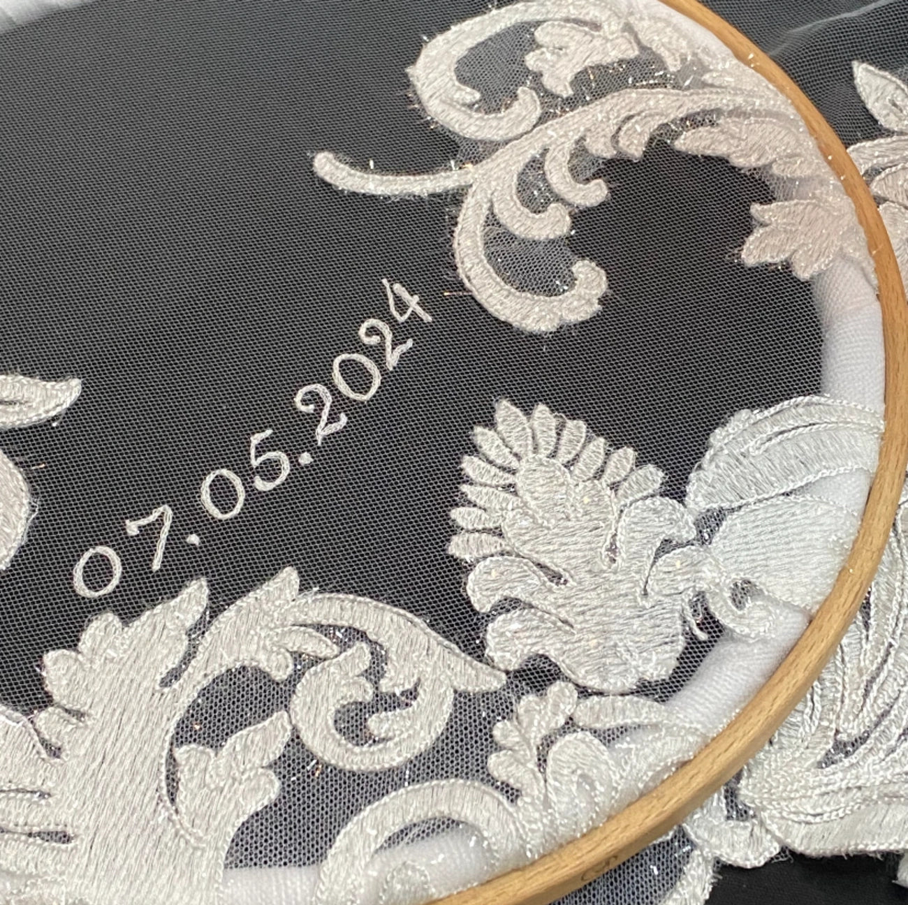 Close-up of a black embroidered fabric with white floral embroidery and the date '07.05.